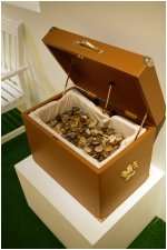 Open wooden box filled with small objects, designed for shaking and tactile sound interaction.