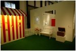 Indoor installation with a striped booth, a bench, the wooden box etc.